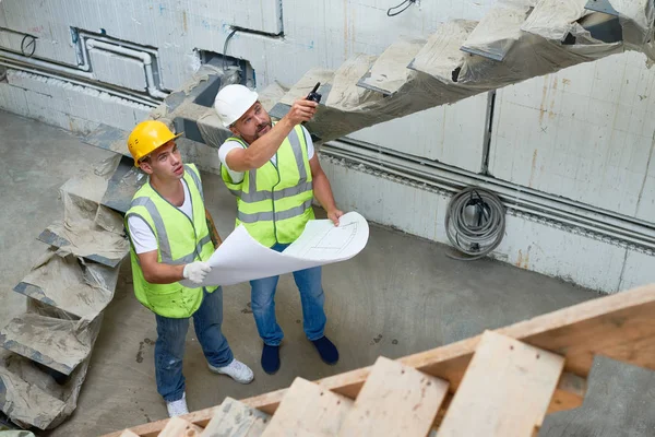 Két Építők Rajta Hardhats Fényvisszaverő Mellény Megvitatása Építése Apartman Épület — Stock Fotó