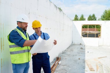 Kavganın ve kat planları Çekme Makinası tartışırken yansıtıcı yelek giyen iki inşaat işçileri portresi