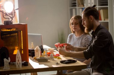 İki yaratıcı genç insanlar, erkek ve kadın, 3d printerlere harcama maddeler yapma küçük plastik modeller, kopya alanı kullanarak portresi