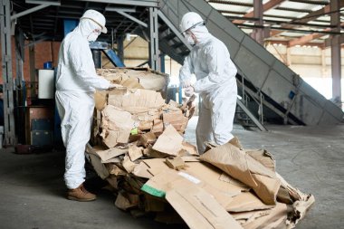 Portre, biohazard giyen iki fabrika işçi sıralama yeniden kullanılabilir karton geri dönüşüm tesisi, kopya alanı uygun