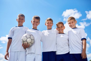 Portre fotoğraf makinesi açık mavi gökyüzü güneş ışığı altında top ile gülümseyen poz genç futbol takımı