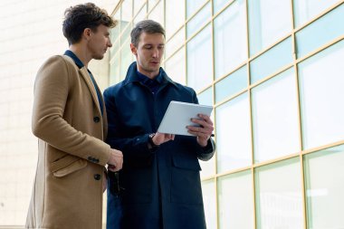 Sonbahar kat dijital kullanarak giyen iki genç iş adamı portresi açık havada modern ofis binası cam ön karşı ayakta tablet, alanı Kopyala