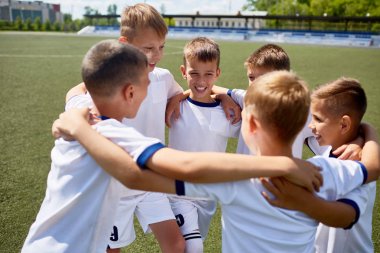 Erkekler mutlulukla futbol sahası üzerinde uygulama sırasında gülümseyen kucaklayan üniformalı ekibi