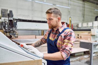 Yakışıklı genç işçi makineleri mekanik kontrol paneli tarafından ayakta ve düğmelere, kopya alanı dükkanda faaliyet portresi