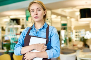 Kameraya bakarak ve dijital tablet kafe iç tutan poz önlük giyen genç garson portresi