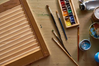 Görünümünün üzerinde sanatçı iş istasyonunun arka plan fırçalar ile DIY sanat projesi için hazırlanan, boya ve ahşap tablo sağlar