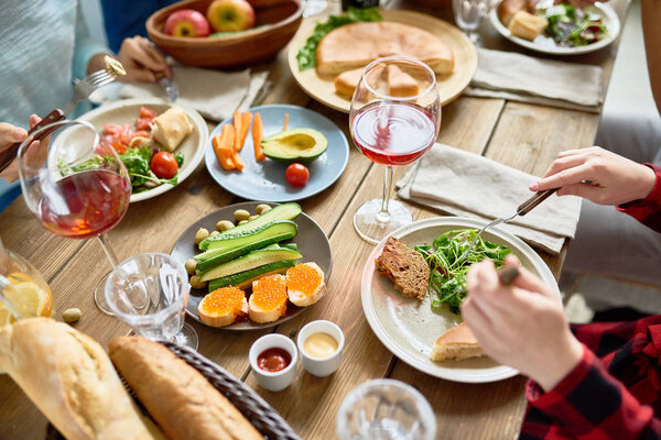Высокий угол крупным планом праздничного стола с вкусной едой на нем и людей, наслаждающихся праздником
