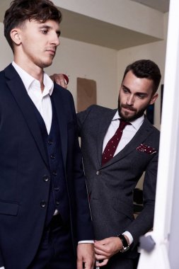 Kendine güvenen genç müşteri tarafından son derece profesyonel terzi mükemmel Klasik takım elbise, Dikiş Atölyesi arka plan üzerinde iç oluşturmak için ölçülen