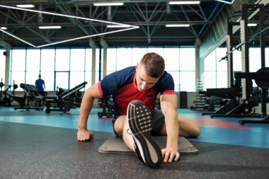 Bacaklar katta modern spor olarak çalışma için Isınma sırasında germe genç adam portresi