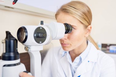 Hastaların görme ofisinde test lamba makine kullanarak sarışın kadın göz doktoruna portresi kesti