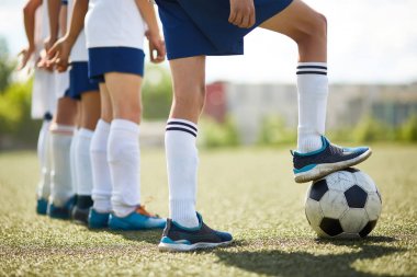 Düşük bölüm portre genç futbol takımı: bacaklar topu güneş ışığı üzerinde adım Kaptan ile satır ayakta çocuklardan