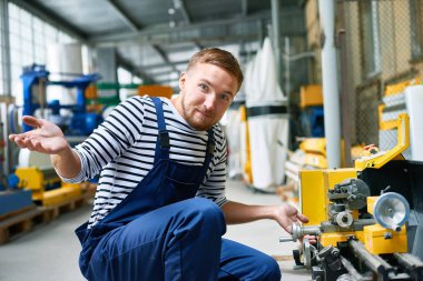 Karışık tamirci fabrikada makinesi ünite düzeltmeye çalışırken sürpriz kamerada bakarak portresi