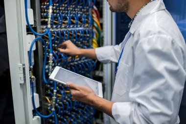 Tanınmayan bilim adamı supercomputer içinde araştırma merkezi ile çalışırken blade sunucu kabloları bağlama önlük giyen orta bölüm portresi