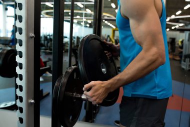 Vücut geliştirme içinde jimnastik salonu için hazırlanıyor standından tanınmaz kaslı sporcu kadar ağır ağırlık alarak orta kesit görünümünü tabaklar