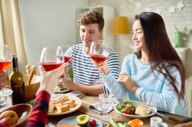 Akşam yemeği birlikte lezzetli yemek, genç adam ve mutlu tatil kutluyor gözlük şarap tungur gülümseyen güzel Asyalı kadın odaklanmak ile büyük masada oturan zevk arkadaş grubu portresi