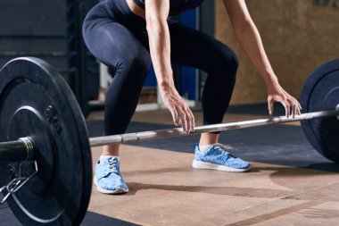 Modern spor olarak ağırlık çalışma sırasında ağır halter kaldırmaya hazırlanıyor ulaşan tanınmaz halde genç kadın portresi düşük bölümü