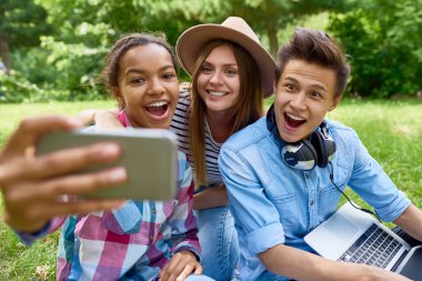 Selfie yeşil'ın bahçesinde açık havada, alan öğrenciler mutlu seyir smartphone kameraya gülümseyen etnik grup