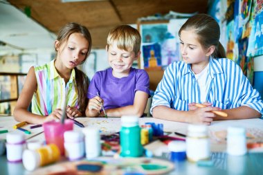 Yaratıcı çocuk masa başında oturan ve guaş, art Studio arka plan üzerinde iç çizim sırasında eğlenmek grup