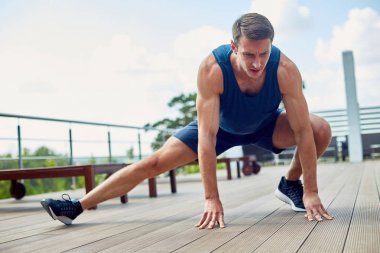 Tam uzunlukta portresi genç atlet bacaklar açık havada Maratonu, güneşli mavi gökyüzü arka plan üzerinde için hazırlarken germe konsantre