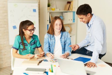 Üç okul seminer için birlikte hazırlanıyor, proje sınıf masada tartışırken çocuk portresi