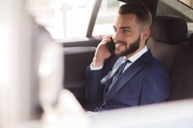 Arkada koltuk lüks araba ve gülümseyerek oturan telefonla konuşan sakallı yakışıklı işadamı portresi