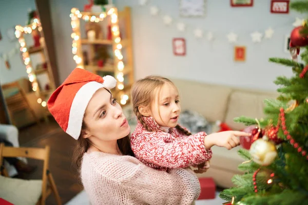 Atrakcyjna Kobieta Kapeluszu Santa Trzymając Jej Córeczkę Ręce Podczas Dekoracji — Zdjęcie stockowe