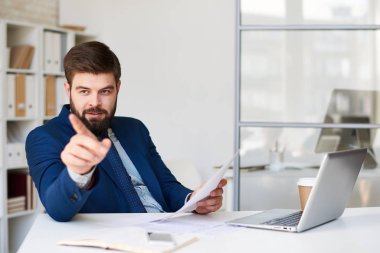 İşaret ve modern ofis masasında çalışırken gülümseyerek emin sakallı işadamı portresi