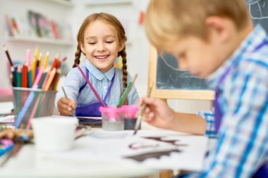 Sevimli küçük kız mutlu okul öncesi çocuk ile birlikte çalışma sanat ve el sanatları dersi tadını çıkarırken gülümseyen portresi