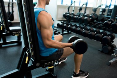 Yan görünüm portre yakışıklı genç adamın kol kasları vücut geliştirme sırasında modern spor salonunda pompalama halter kaldırma