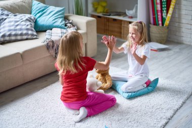 Pat bir pasta oynayan neşeli küçük kızlar tadını çıkarırken birbirinizin rahat oturma odasında şirket