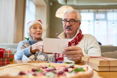 Seven üst düzey çift Noel yemeği kafeterya sırasında aile fotoğraflarına bakarak portresi