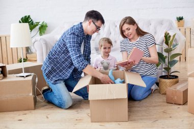 Sevgi dolu genç aile yeni daire ve malzeme ile/açma karton kutular oturma odasında bir araya