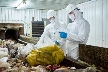 Geri dönüşümlü plastik ve karton işleme tesisi atık, Konveyör bant üzerinde sıralama biohazard giyen iki işçi portresi uygun