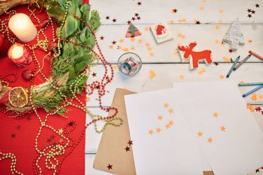 Noel çelenk ve mumlar, el yapımı oyuncak, kalem ve kağıt küçük onların sahibi için bekleyen ahşap masa yakın çekim çekim süslenmiş