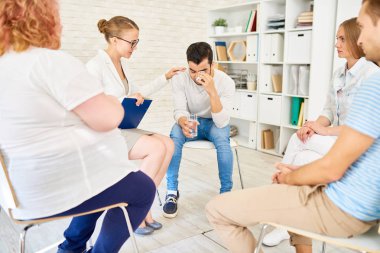 Genç adam onu teselli kadın psikiyatrist ile grup terapisi toplantı destek daire içinde ağlıyor portresi
