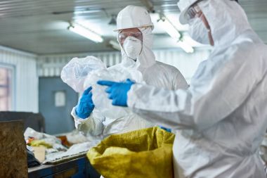 Portre biohazard giyen iki işçilerin çalışma çöp ve yeniden kullanılabilir plastik ayakta konveyör kayışı ile Ayırma tertibatları işleme atık, uygun