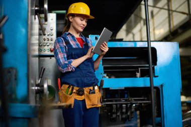 Dijital tablet ile güç üniteleri modern fabrikasında çalışırken kullanma kadın makine operatörünün portresi