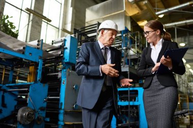 Kendine güvenen üst düzey iş adamı takım modern fabrikası gece turunu veren eller içinde clipboard çekici genç kadın