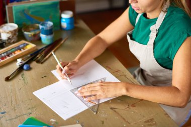Genç kadın ile atölye tahta masada oturan sanat ve el sanatları projesi için kalem kroki çizim yüksek açı