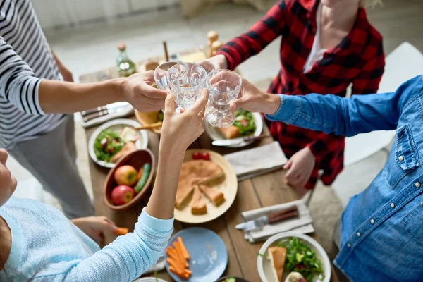 一群朋友一起享用晚餐 站在大餐桌旁 吃着可口的食物和敬酒 专注于无比的眼镜庆祝节日 — 图库照片