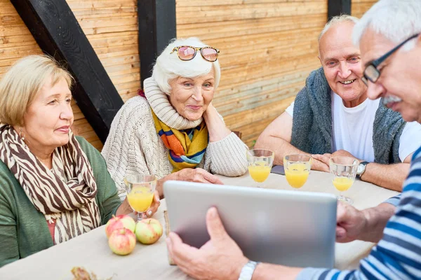裏庭で友達と週末を過ごす テーブルに座って ザブレブ ジュース中にノート パソコンで面白いビデオを見て元気な高齢者 — ストック写真