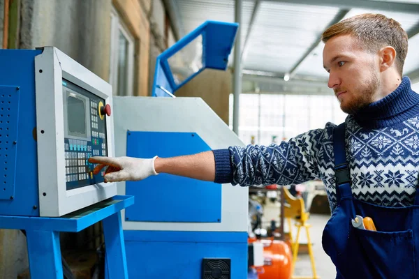 近代的な工場で機械ユニットを運営して電子制御パネルのボタンを押すと若い男の側ビュー肖像画 — ストック写真