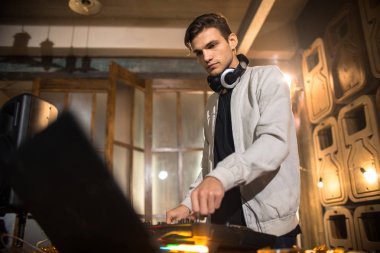 Yan görünümü portresi trendy genç Dj Mikser kullanarak ve dizüstü ekran gece kulübü parti, kopya alanı bakarak müzik çalma