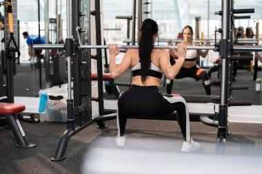 Arkadan görünüşü güzel genç kadın ile Halter modern bir spor salonu ayakta pencere karşı eğitim