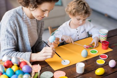 Paskalya tatili için süslemeler yapma sevimli küçük oğlu ile Paskalya yumurta boyama genç kadın portresi