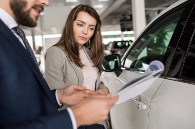 Lüks araba showroom seçerken araba satıcısı için dinleme modern genç kadın portresi