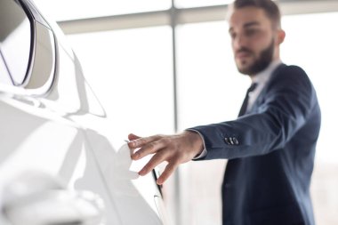 Hafifçe yumuşak beyaz lüks araba, ön plan, kopya alanı odaklanmak metalden dokunmadan yakışıklı işadamı portresi