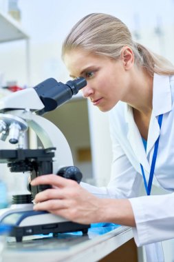 Yan görünüm portre genç kadın bilim Fen laboratuarı tıbbi araştırma üzerinde çalışırken mikroskobu arıyorsunuz
