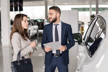 Genç kadın lüks araba showroom seçim ona yardım için söz yakışıklı araba satıcısı portresi