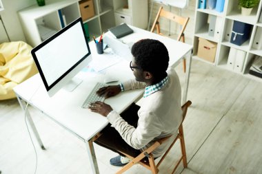 Ofis Masası oturma ve modern bilgisayar yardımı ile iş ortağı için görsel sunum hazırlama çalışkan Afrikalı-Amerikalı girişimci yüksek açılı görünüş.